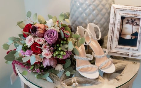 a bouquet of flowers and white heels on a desk