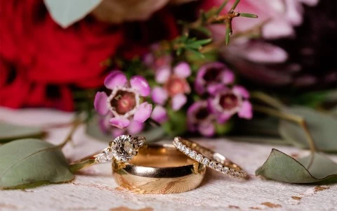 close up of rings with a floral bouquet behind it