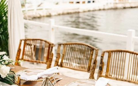 a table with chairs and a table with a body of water in the background