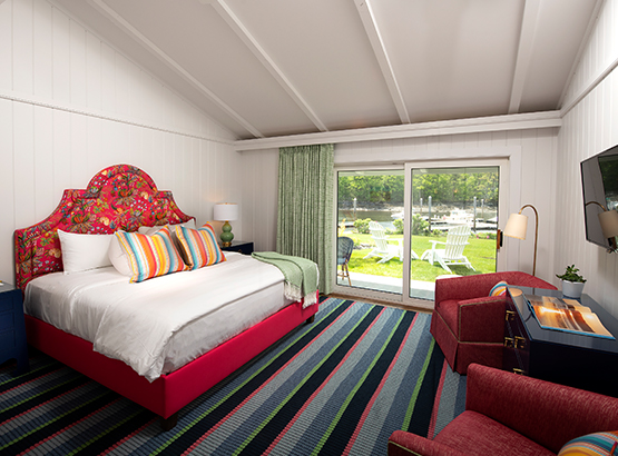 bedroom with bed and two arm chairs, a mounted tv, and a sliding glass door