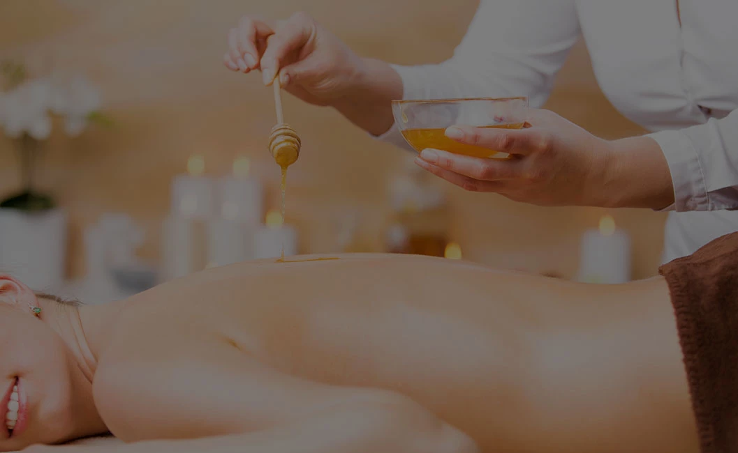 person receiving a body treatment including honey on their back