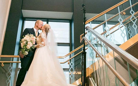 bride and groom kissing at the top of a staircase
