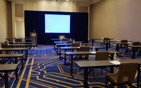 meeting room with three rows of desks and a big screen 0