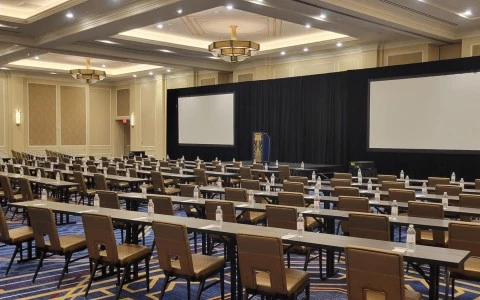 big conference room with a big stage and desks with waters on it12