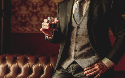 Close up of man in suit holding glass of alcohol
