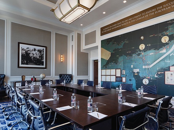 meeting room with dark wood table and black chairs with water bottles, pens and pads on the table 8