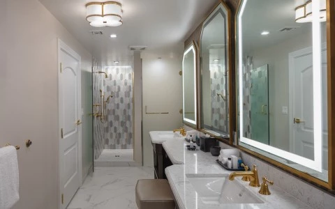 bathroom with three wall mirrors and two sinks showing a shower at the end 2