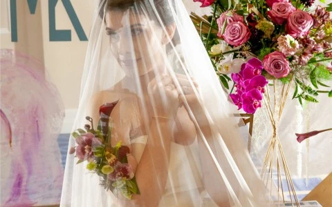 close up photo of a woman with a wedding dress with a crystal wall behind and some flowers2