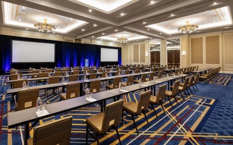conference room with two big screens with so many chairs and desks 20