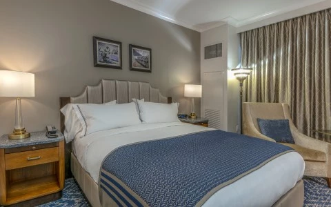 a bed with a blue blanket and a lamp in a room