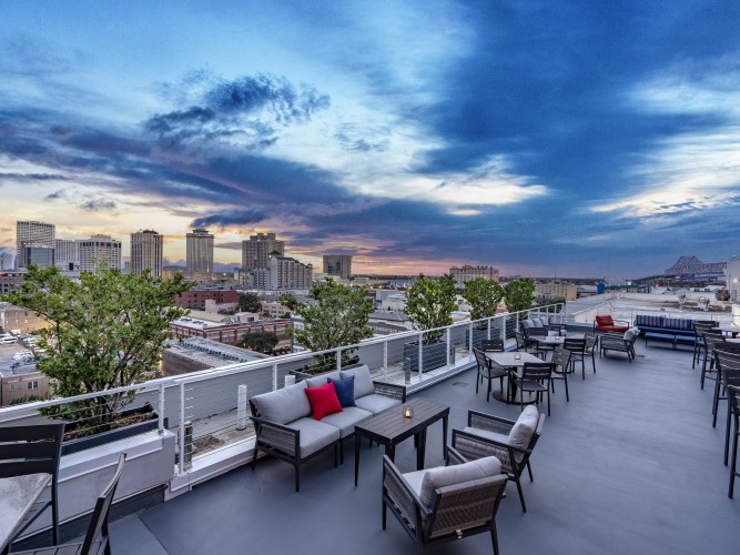 a rooftop patio with chairs and tables and trees 1