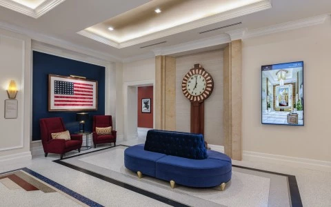 public space with a blue sofa and two red chairs with a USA flag on the wall 4