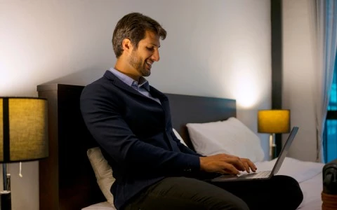 a man sitting on a bed using a laptop