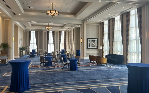 a room with blue carpet and tables and chairs