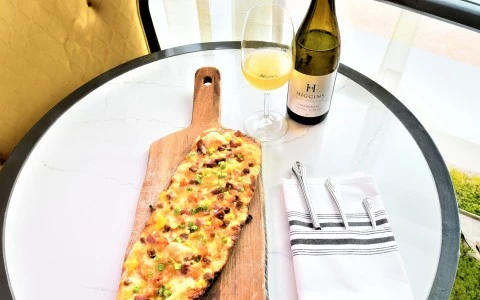 a pizza on a wooden board next to a wine bottle30