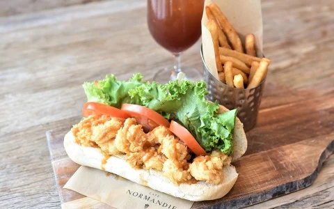 a sandwich with fried chicken and tomatoes on a wooden surface33