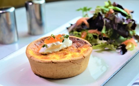 a small tart with cream and green onions on a plate40
