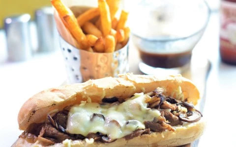 a sandwich with cheese and mushrooms on top and a cup of fries41