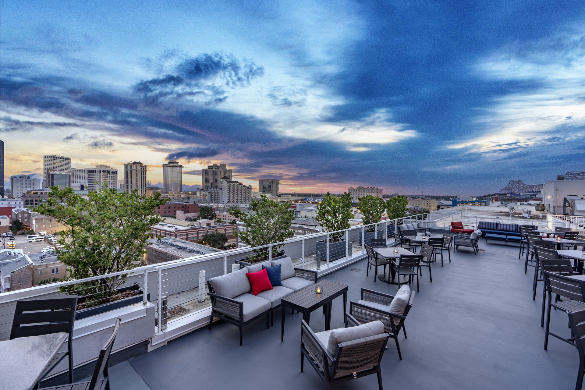 a rooftop patio with chairs and tables and trees