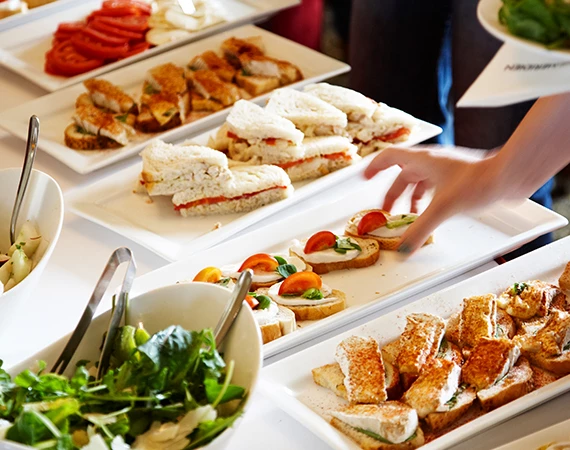 a person reaching for sandwiches on plates