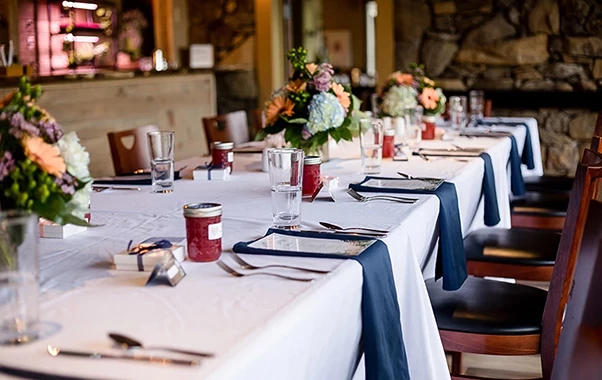 a table with white tablecloths and glasses and a bouquet of flowers