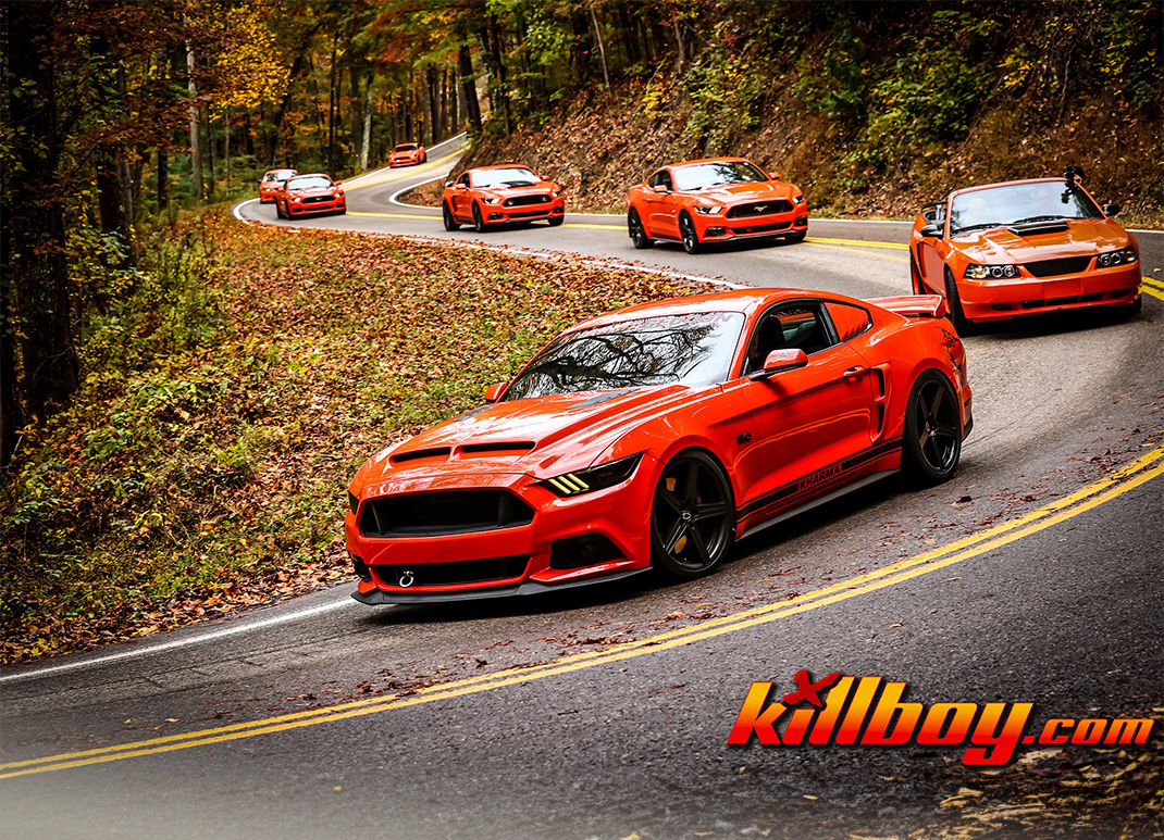 a group of orange sports cars driving on a winding road