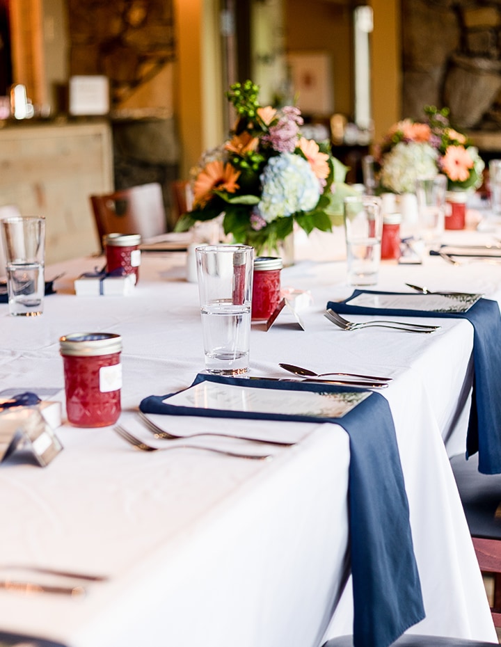 a table with white tablecloths and glasses and a bouquet of flowers
