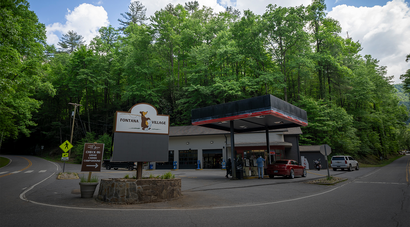 a gas station with a sign and a car in front of it