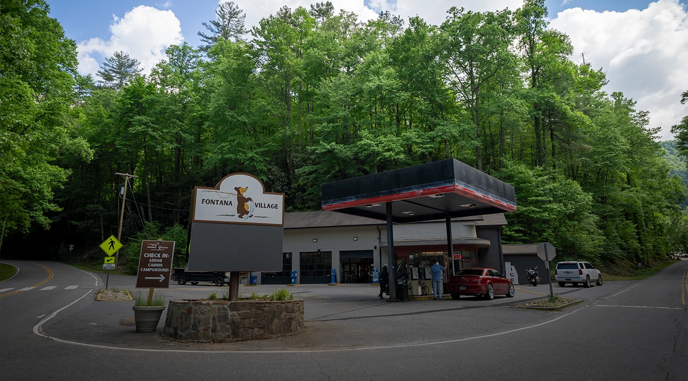 a gas station with a sign and a car in front of it