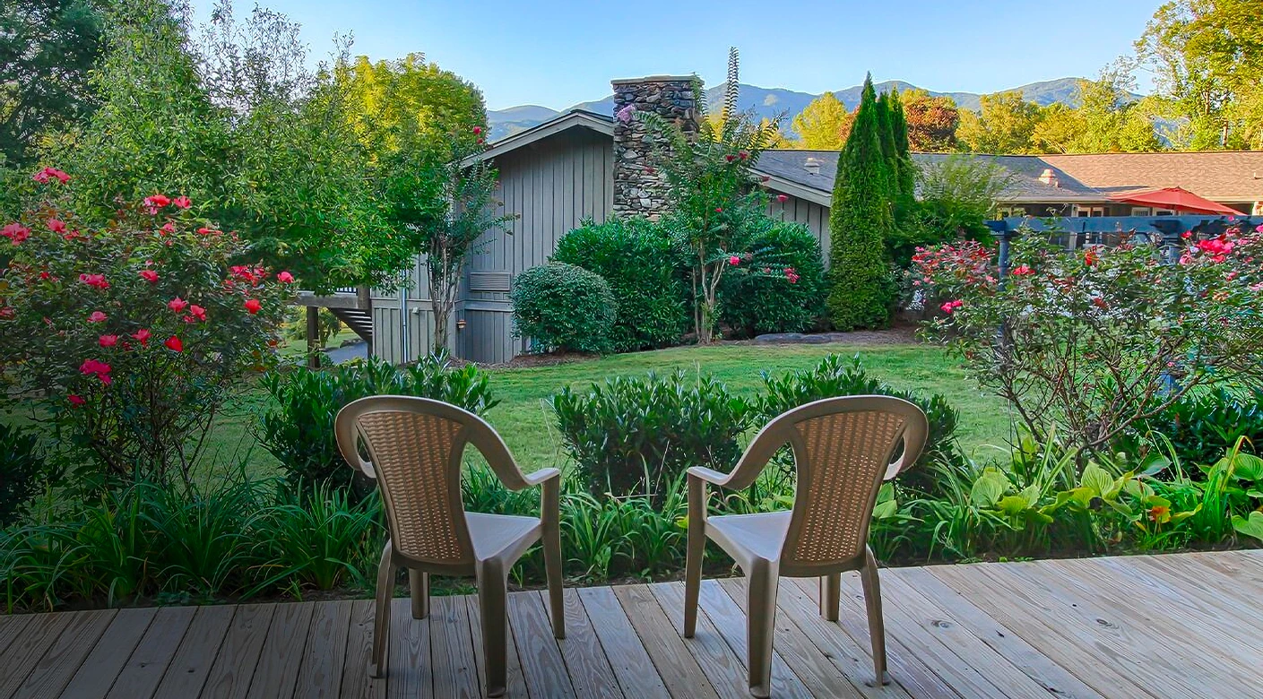 a deck with chairs overlooking a yard