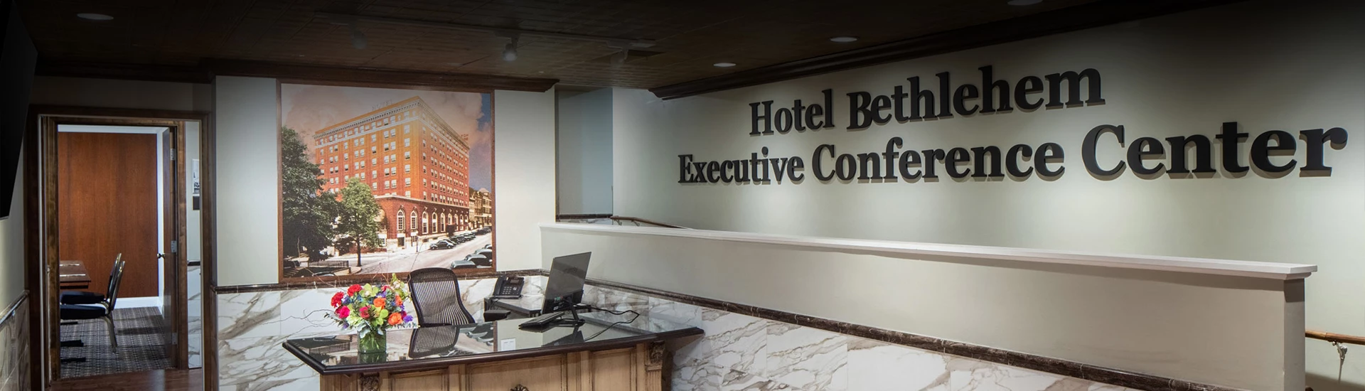 a desk and a laptop in front of a hotel reception