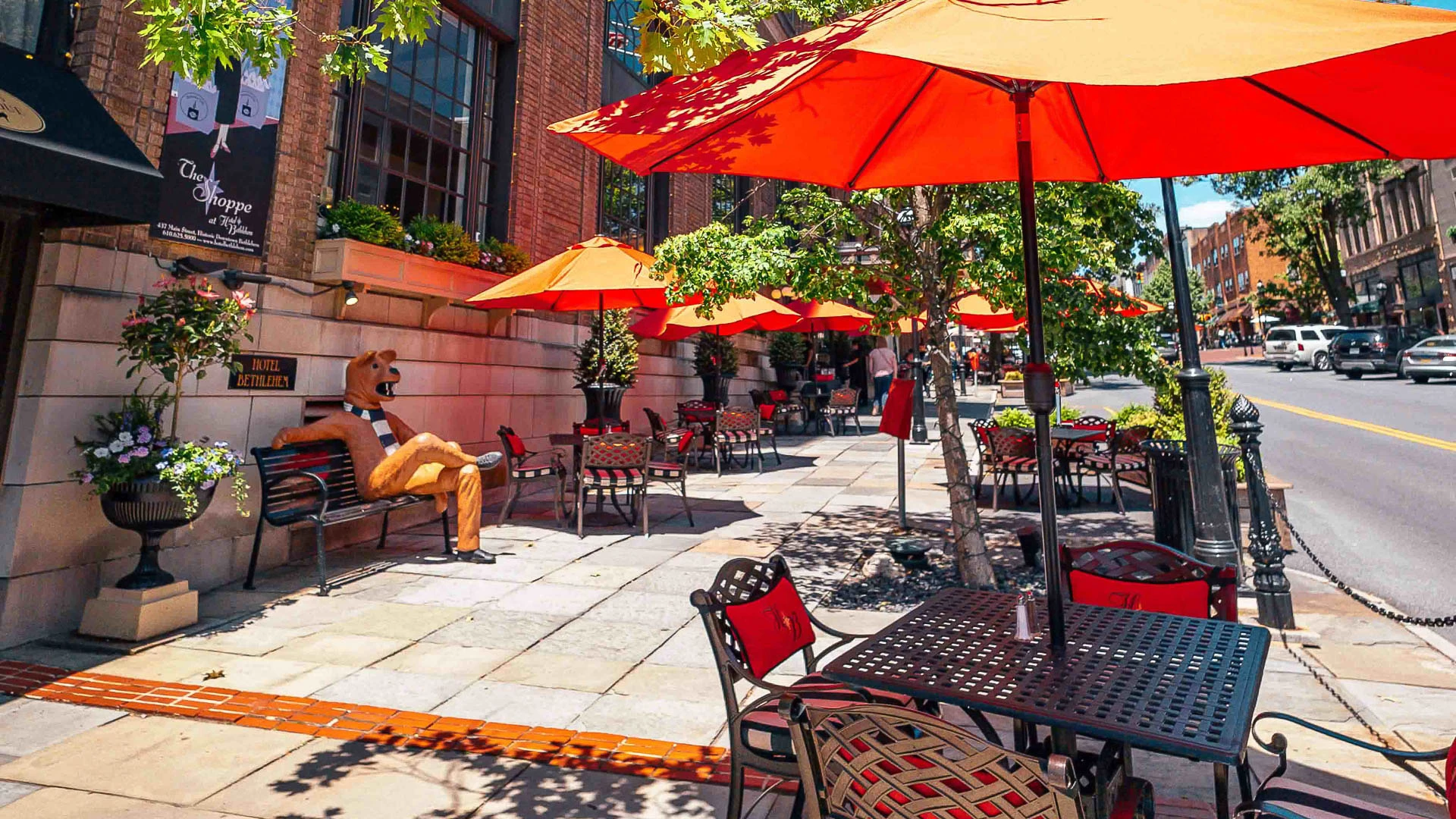 a man sitting on a bench outside with an orange umbrella