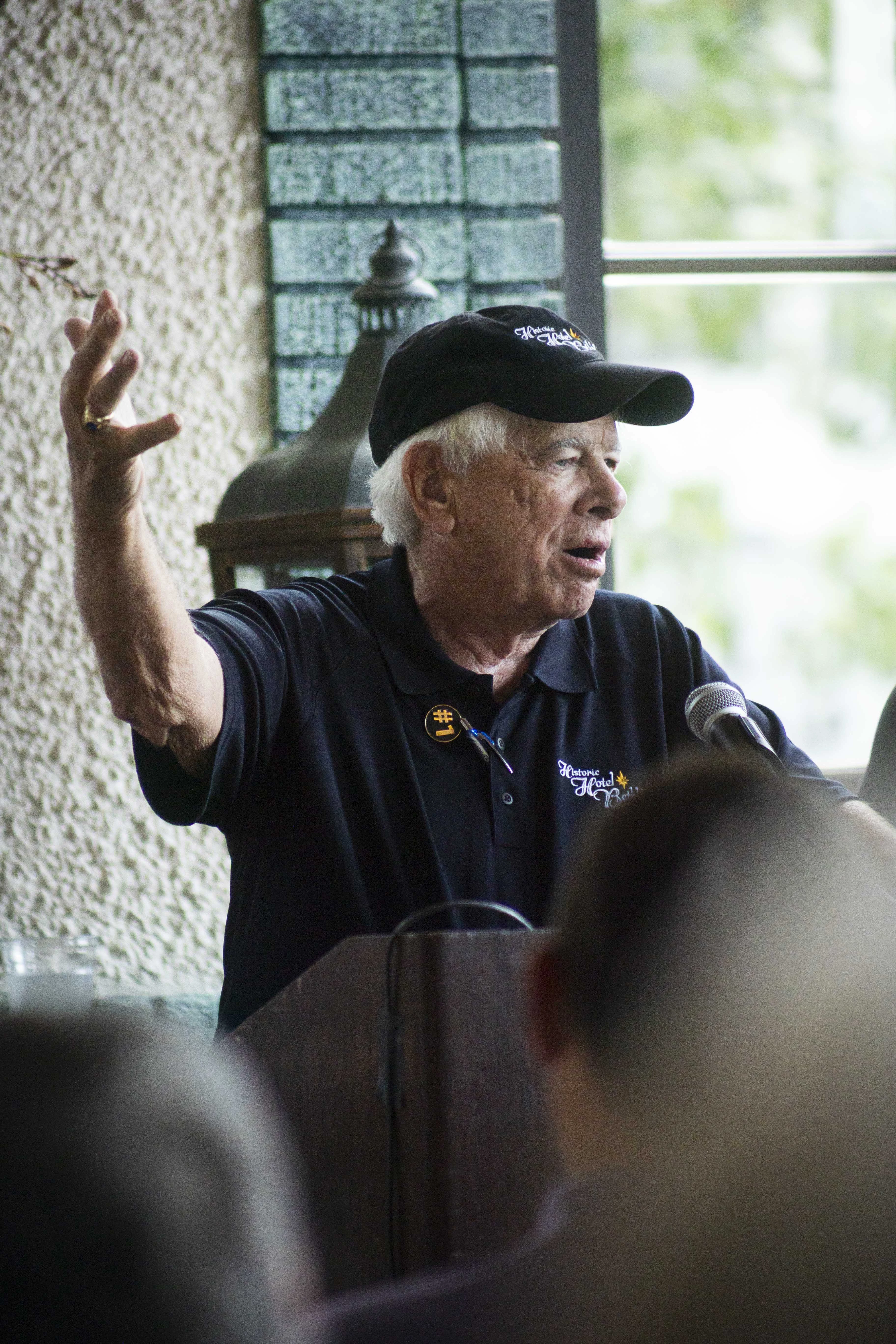 a man in a black hat speaking into a microphone
