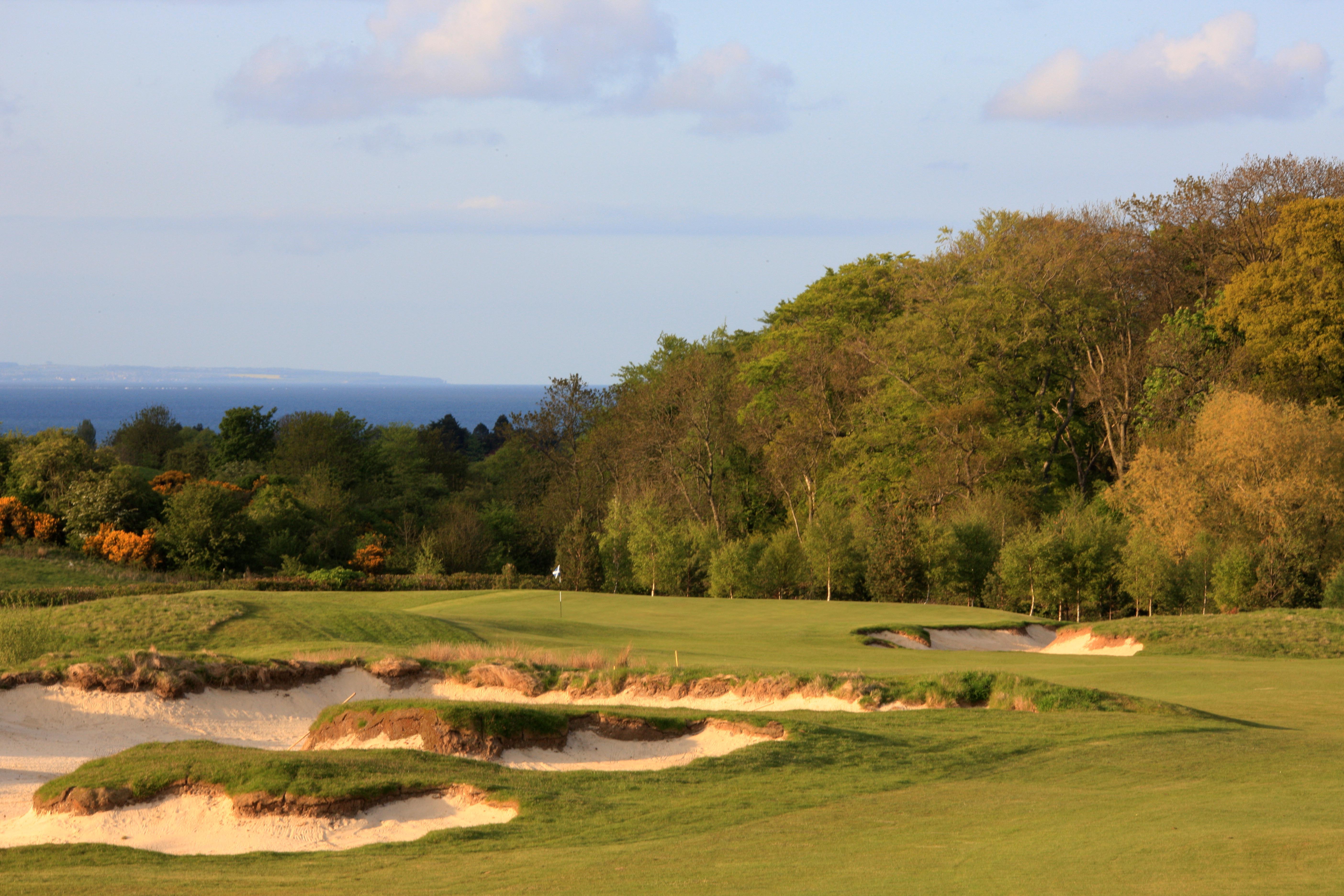 a golf course with sand bunkers and trees
