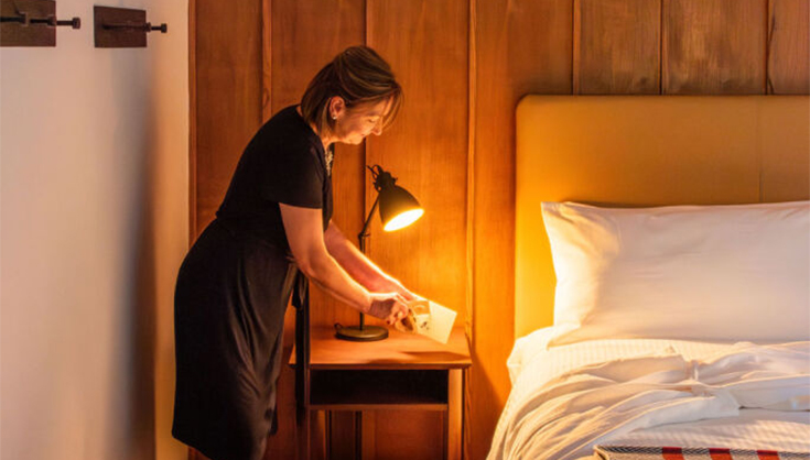 a woman standing next to a bed