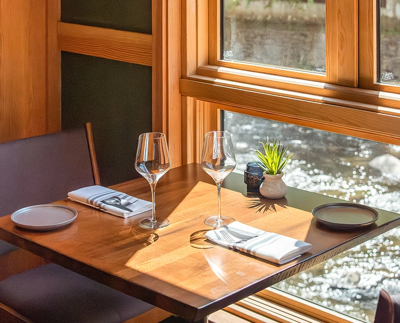 a table with wine glasses and plates and a plant on it