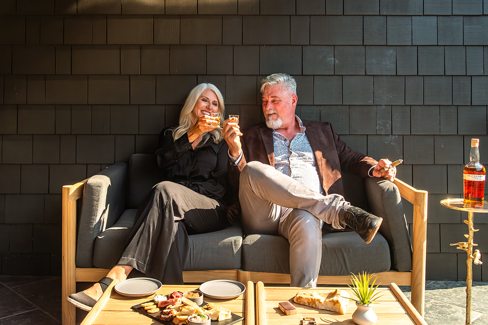 a man and woman sitting on a couch with drinks