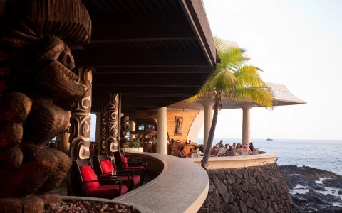 Side view of a balcony with rock carved columns and red chairs