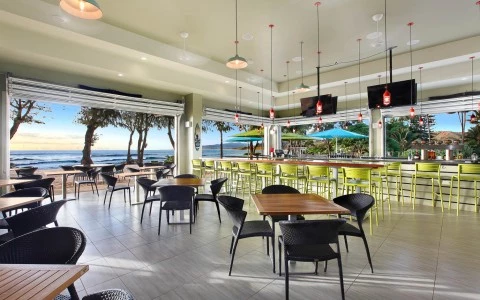 A hotel restaurant full of black chairs and wooden tables