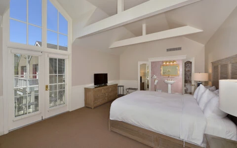 hotel bedroom with high arch ceilings and wide window with view