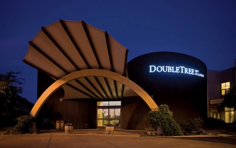 hotel entrance with arch and vegetation during dusk