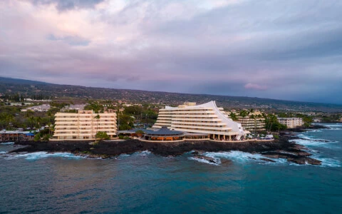 deep blue ocean waves crashing upon volcanic shore of the royal kona resort during sunset