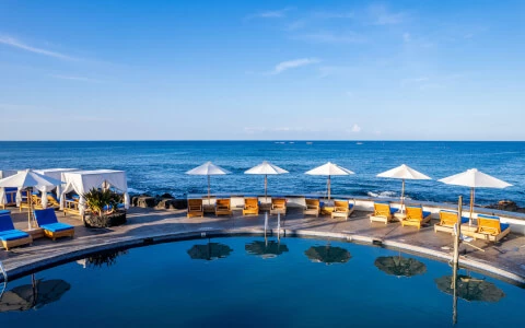 resort pool with lounge chairs overlooking ocean during daytime