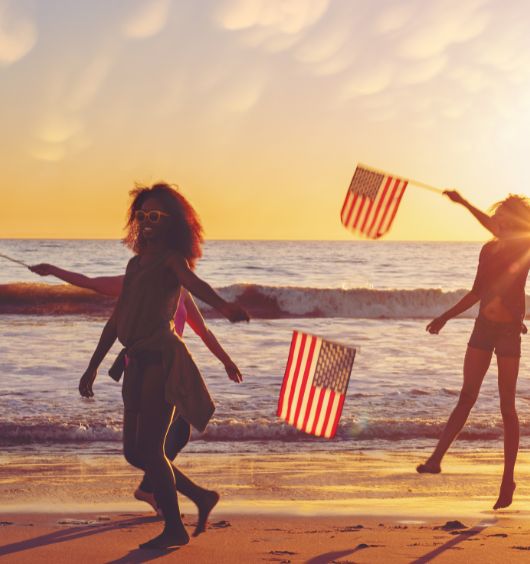 a group of people running on a beach with flags
