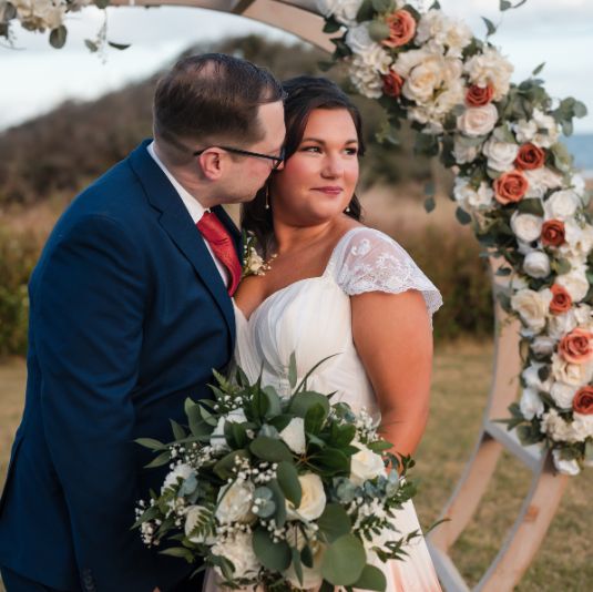 a man and woman standing under a flower arch