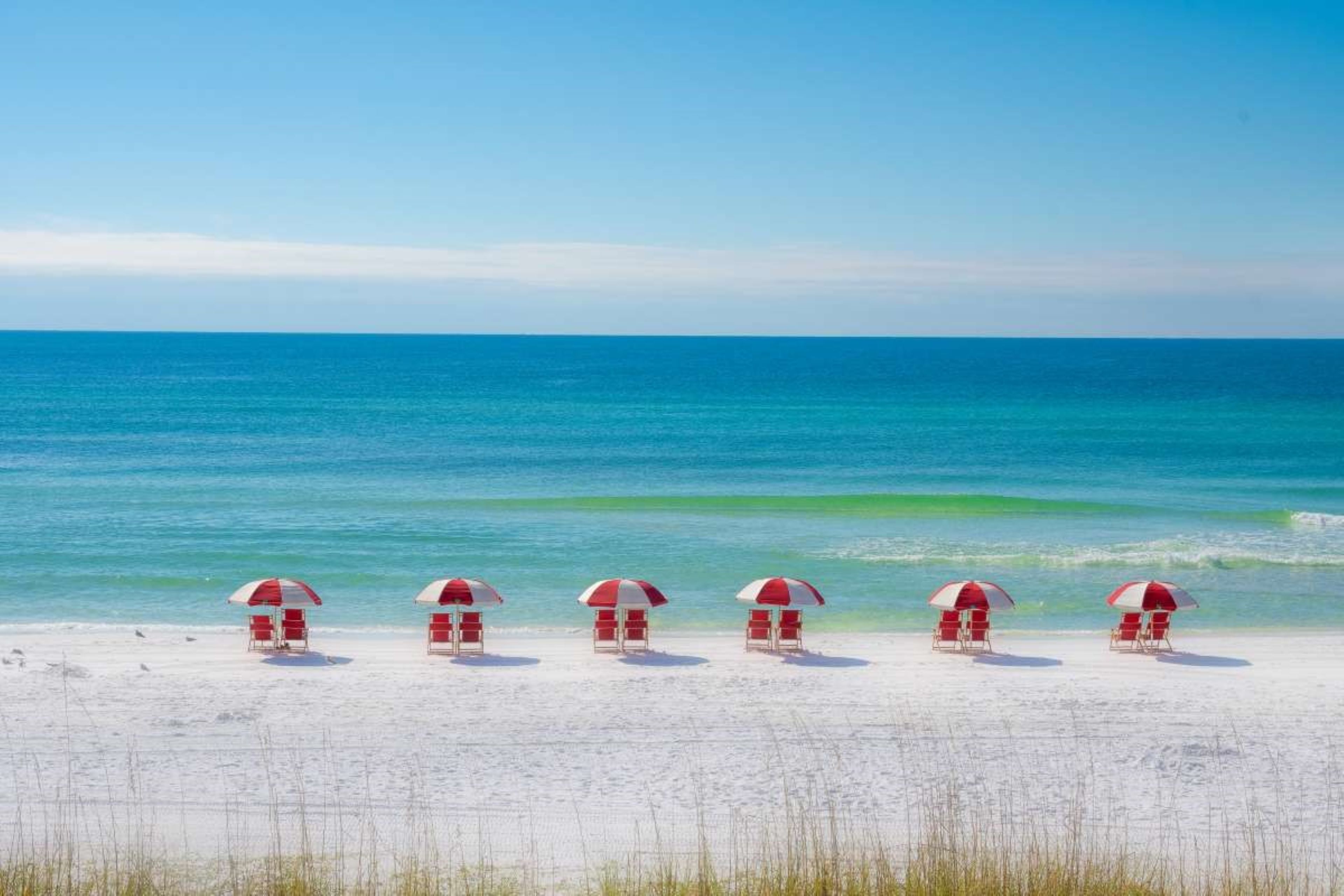a group of red and white umbrellas on a beach