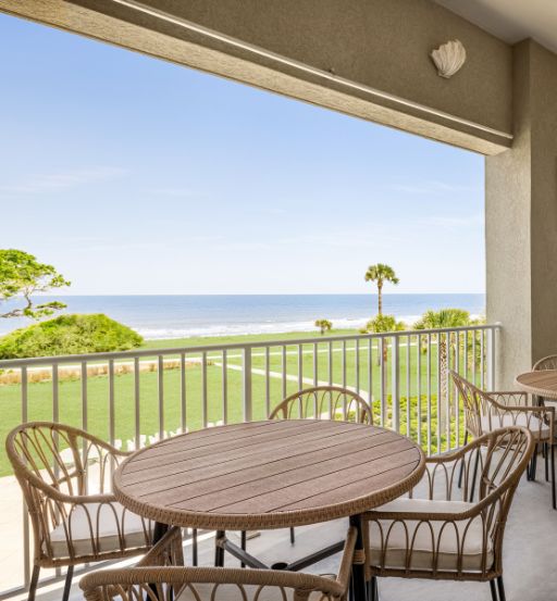 a table and chairs on a balcony overlooking the ocean