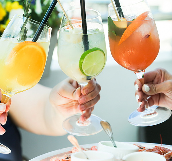 A group of hands holding up cocktails for a toast