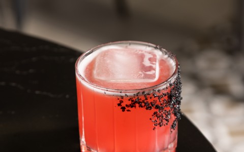 a glass with a drink and ice on a table