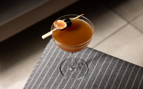 a glass with brown liquid and a fruit on top